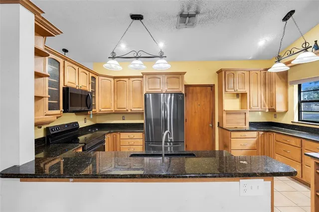 a kitchen with stainless steel appliances granite countertop a sink a stove and a wooden cabinets
