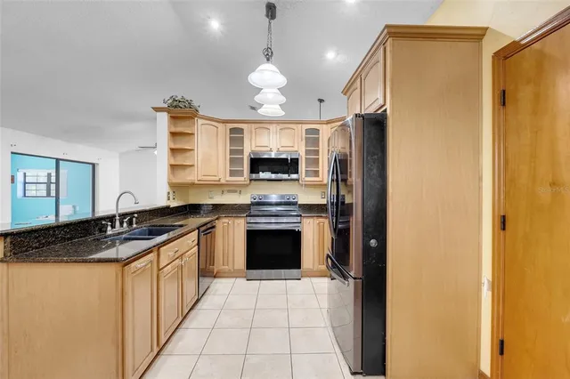 a kitchen with granite countertop a sink stainless steel appliances a counter top space cabinets and a window