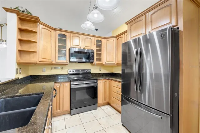 a kitchen with stainless steel appliances granite countertop a refrigerator a stove and a sink with wooden floor