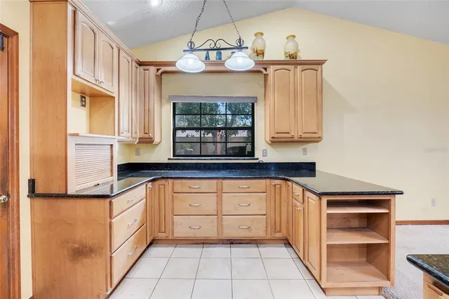a kitchen with granite countertop a stove a sink and a refrigerator