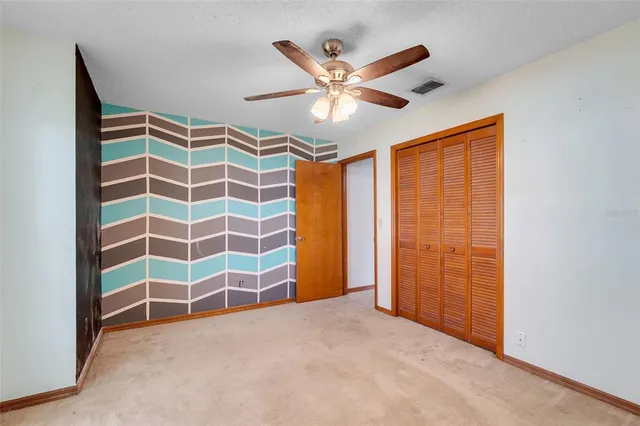 an empty room with windows and fan