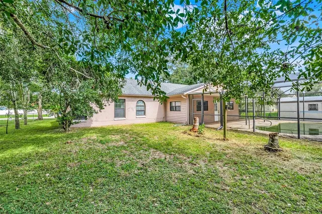 a view of a house with a yard and large trees