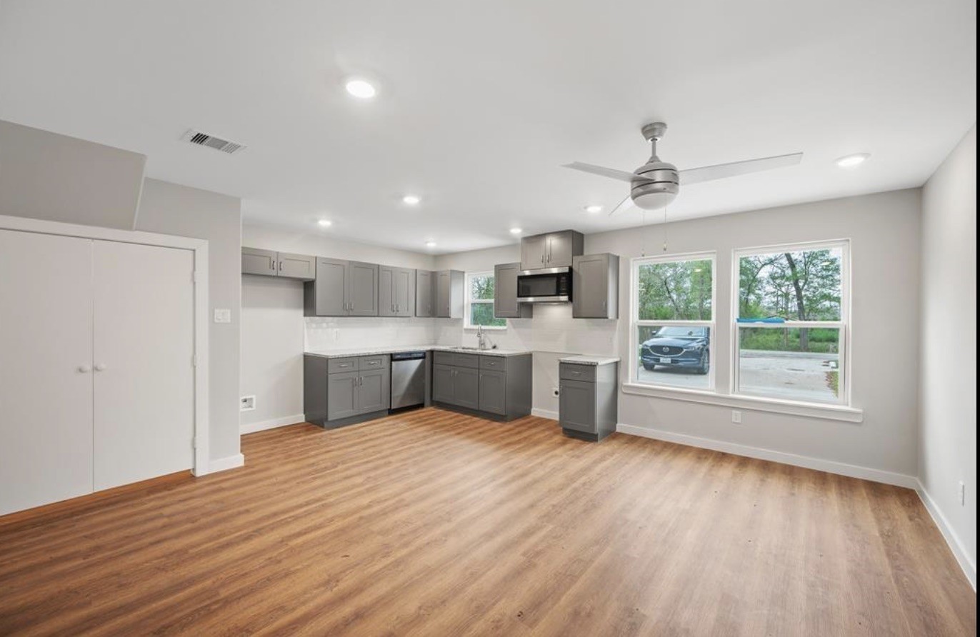 a large white kitchen with kitchen island a sink wooden floor and a refrigerator
