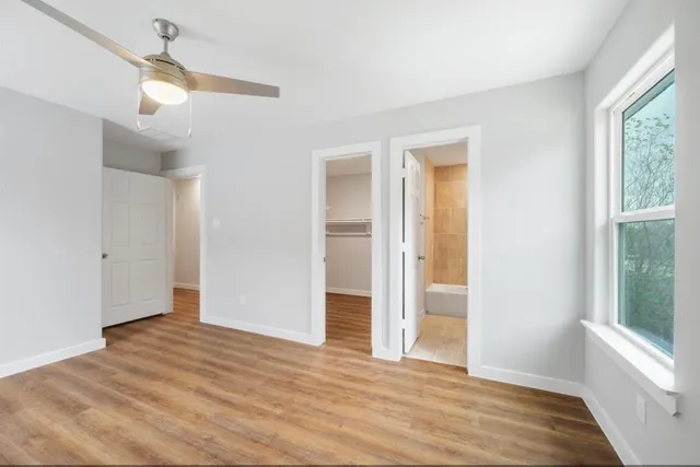 a view of an empty room with wooden floor and a window