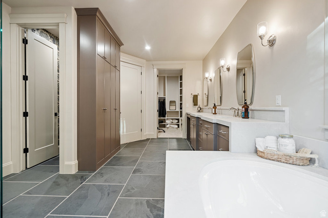 1141 South Oak Leaf Lane Springville, UT 84663 - Photo 62 of 147 Spacious bathroom featuring large format stone tile flooring, a built-in soaking tub, and a double vanity with undermount sinks and wall-mounted sconces