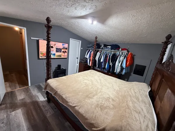 a bed sitting in a bedroom next to a flat screen tv with kitchen view