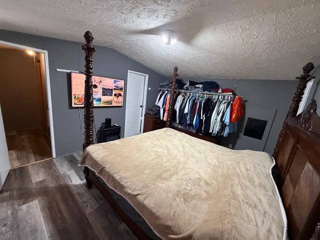 a bed sitting in a bedroom next to a flat screen tv with kitchen view