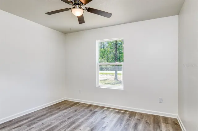 an empty room with a window and a fan