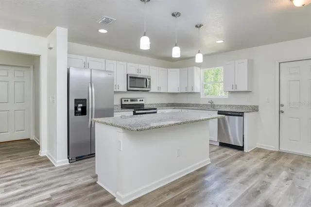 a kitchen with kitchen island granite countertop a sink cabinets and stainless steel appliances