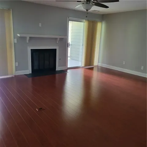 an empty room with wooden floor fireplace and windows