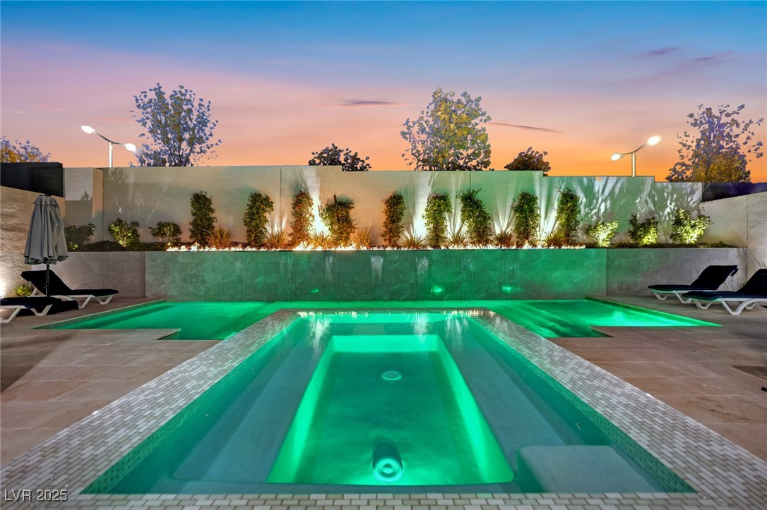 397 Highview Rdg Avenue Las Vegas, NV 89138 - Photo 19 of 97 Pool at dusk featuring a patio, a pool with connected hot tub, and a fenced backyard