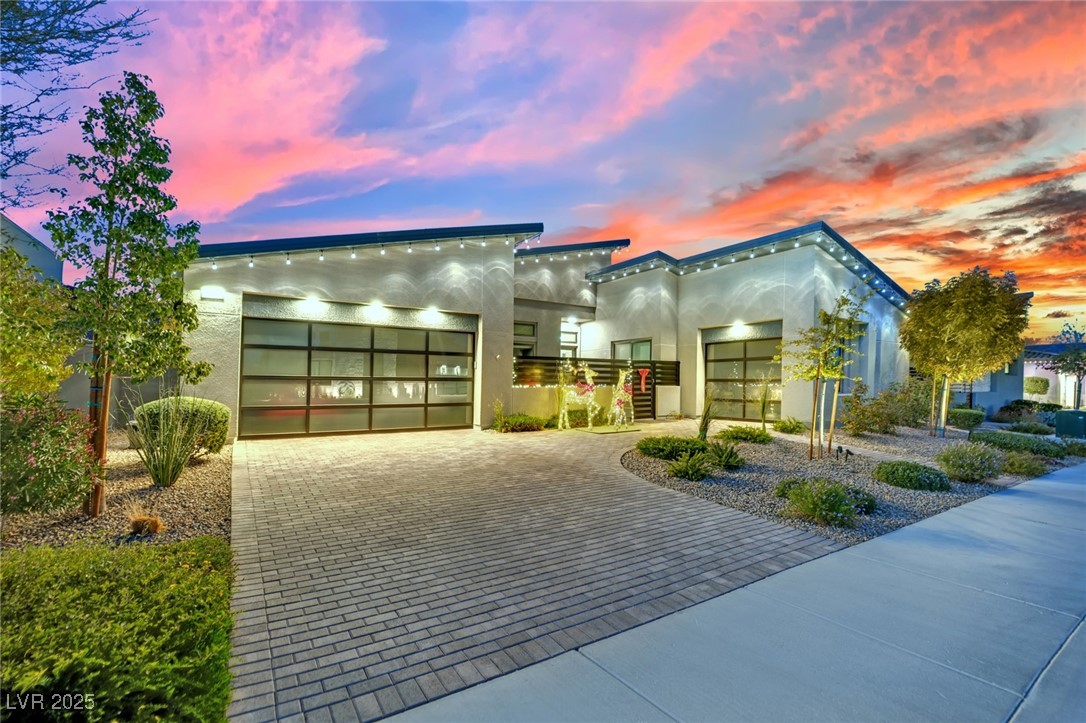 397 Highview Rdg Avenue Las Vegas, NV 89138 - Photo 2 of 97 Contemporary house featuring stucco siding, decorative driveway, and an attached 3 car garage with glass and steel doors