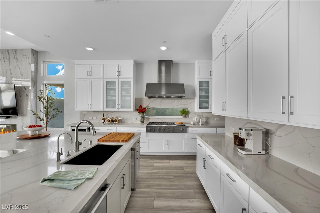 397 Highview Rdg Avenue Las Vegas, NV 89138 - Photo 41 of 97 Kitchen with white cabinetry, light stone counters, glass insert cabinets, backsplash, and wall chimney range hood