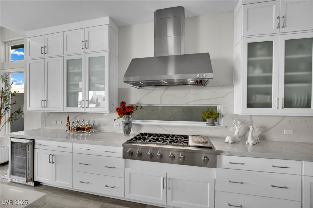 397 Highview Rdg Avenue Las Vegas, NV 89138 - Photo 42 of 97 Kitchen featuring wall chimney exhaust hood, white cabinets, glass insert cabinets, backsplash, and light stone countertops