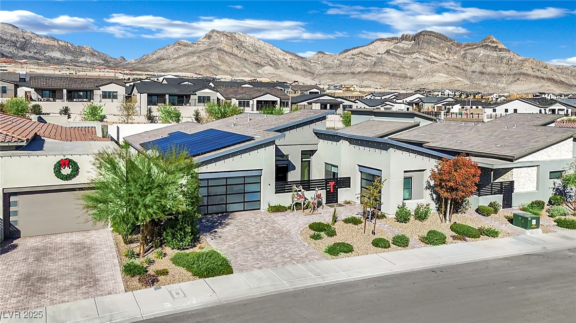 397 Highview Rdg Avenue Las Vegas, NV 89138 - Photo 77 of 97 View of front facade featuring solar panels, a residential view, a garage, a mountain view, and decorative driveway