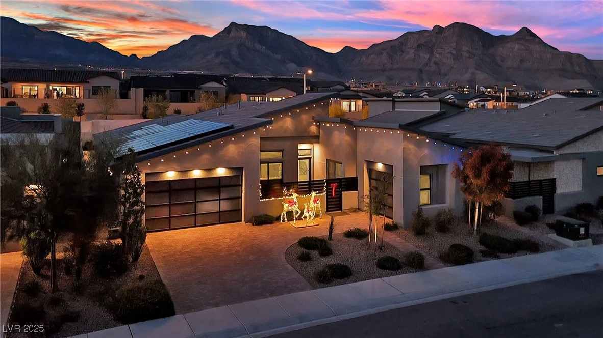 397 Highview Rdg Avenue Las Vegas, NV 89138 - Photo 94 of 97 Modern home with decorative driveway, a mountain view, an attached garage, stucco siding, and solar panels