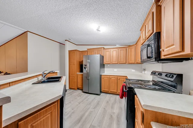 a kitchen with stainless steel appliances granite countertop a refrigerator a stove and a sink with wooden floor