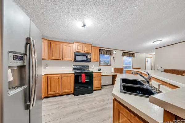 a kitchen with stainless steel appliances granite countertop a refrigerator a stove and a sink with wooden floor