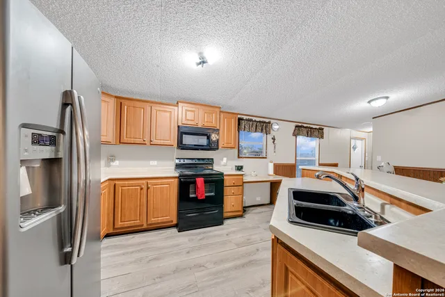 a kitchen with stainless steel appliances granite countertop a refrigerator a stove and a sink with wooden floor