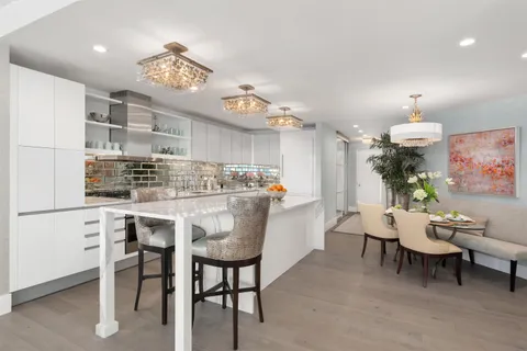 a kitchen with kitchen island a dining table chairs cabinets and stainless steel appliances