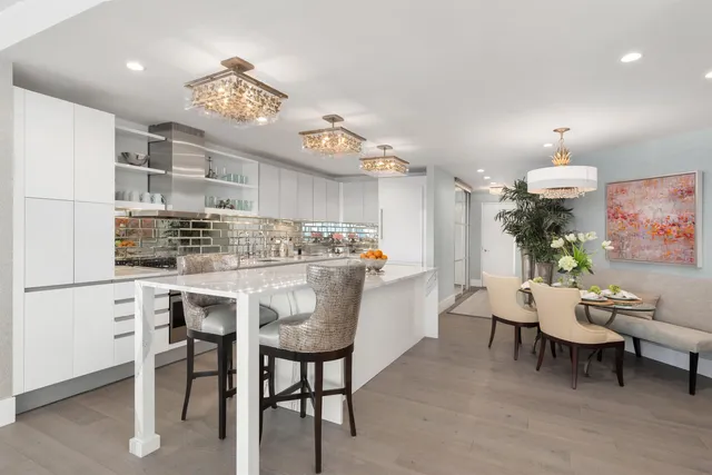 a kitchen with kitchen island a dining table chairs cabinets and stainless steel appliances