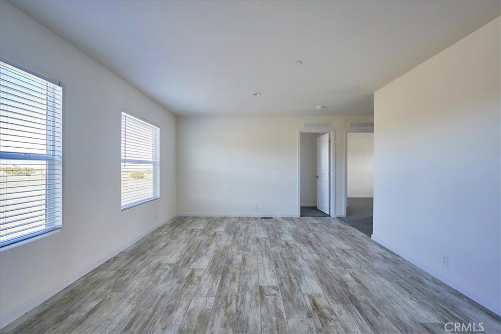 12012 Lager Road Phelan, CA 92371 - Photo 16 of 35 an empty room with wooden floor and windows