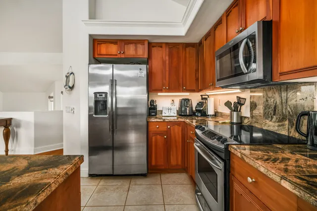 a kitchen with stainless steel appliances granite countertop a refrigerator a stove and a sink