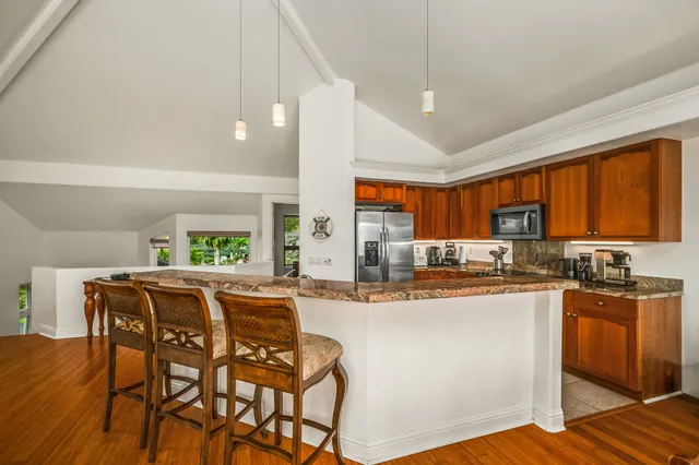a kitchen with stainless steel appliances granite countertop wooden cabinets a dining table and chairs
