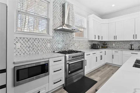 a kitchen with stainless steel appliances a refrigerator a stove a sink and white cabinets with wooden floor