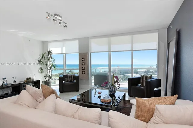 a living room with furniture large windows and wooden floor