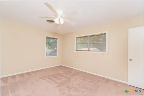 an empty room with a window and ceiling fan