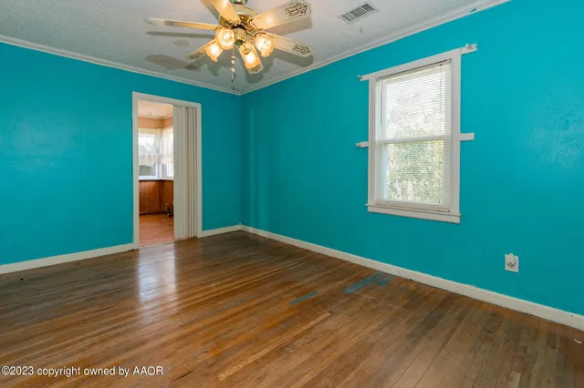 a view of empty room with wooden floor and fan