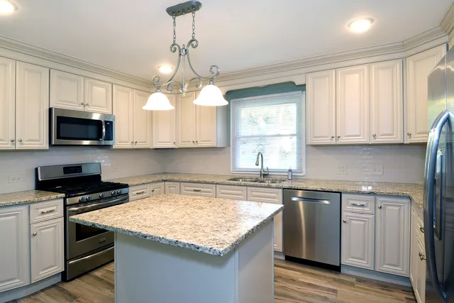 a kitchen with kitchen island granite countertop a stove and a sink