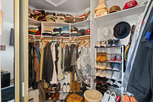 a view of walk in closet with clothes and shoes