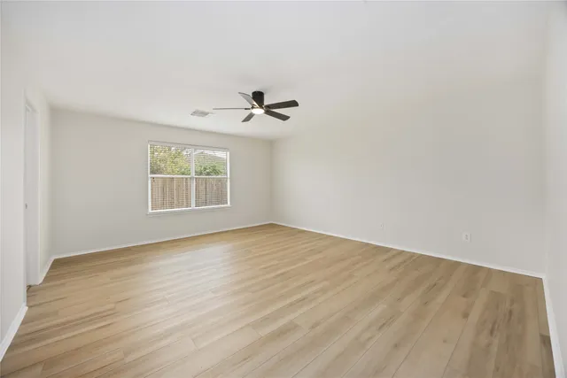 an empty room with a window and a ceiling fan