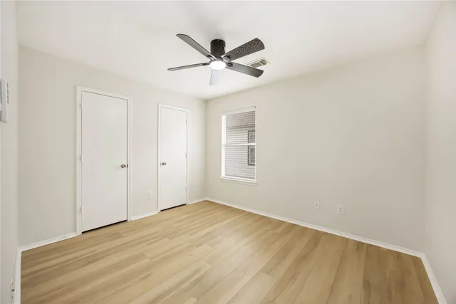 a view of a room with wooden floor and a ceiling fan