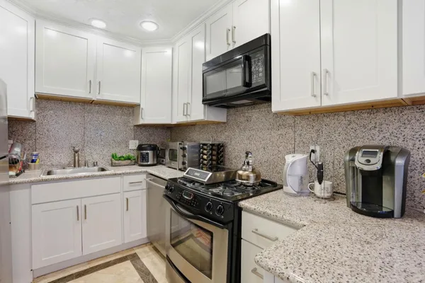 a kitchen with stainless steel appliances granite countertop white cabinets sink and stove