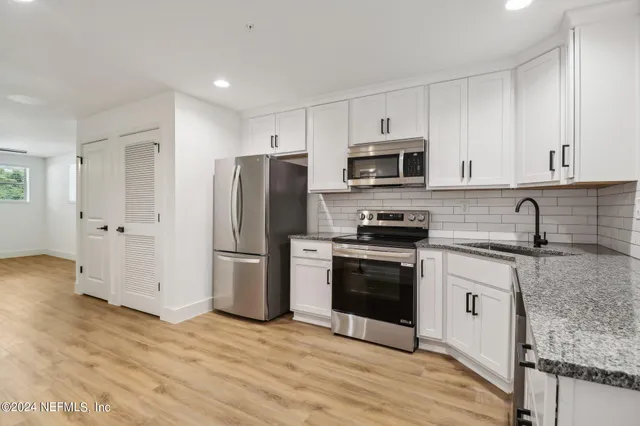 a kitchen with a sink a stove a refrigerator and cabinets