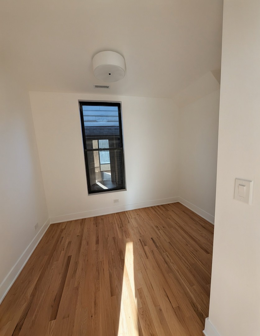 916 North Noble Street, Unit 2F Chicago, IL 60642 - Photo 17 of 22 a view of an empty room with wooden floor and a window