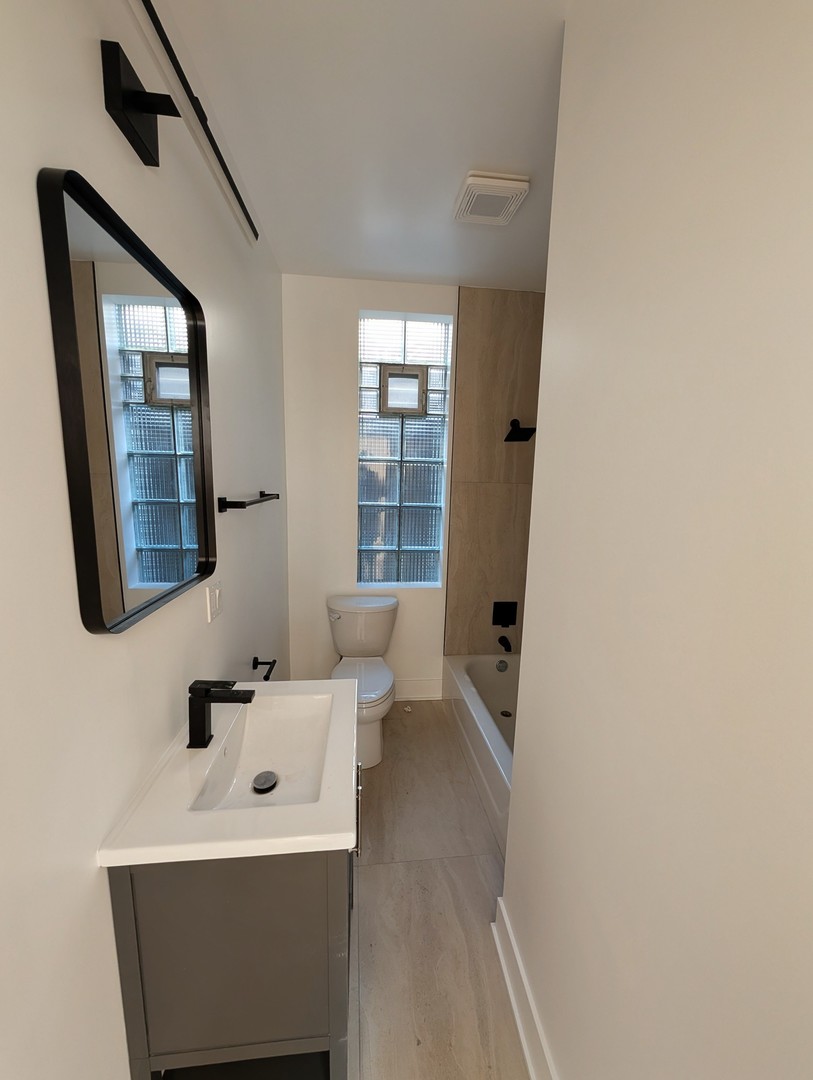 916 North Noble Street, Unit 2F Chicago, IL 60642 - Photo 19 of 22 a bathroom with a sink a mirror and a toilet