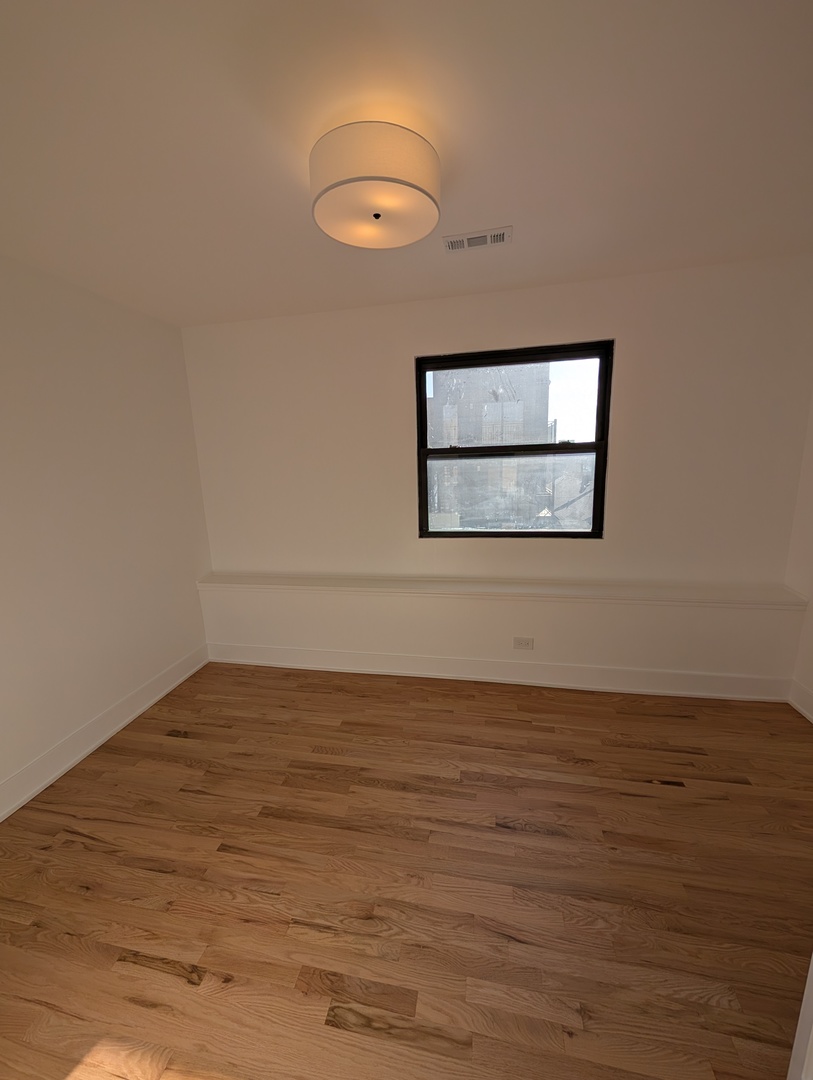 916 North Noble Street, Unit 2F Chicago, IL 60642 - Photo 8 of 22 a view of an empty room with wooden floor and a window