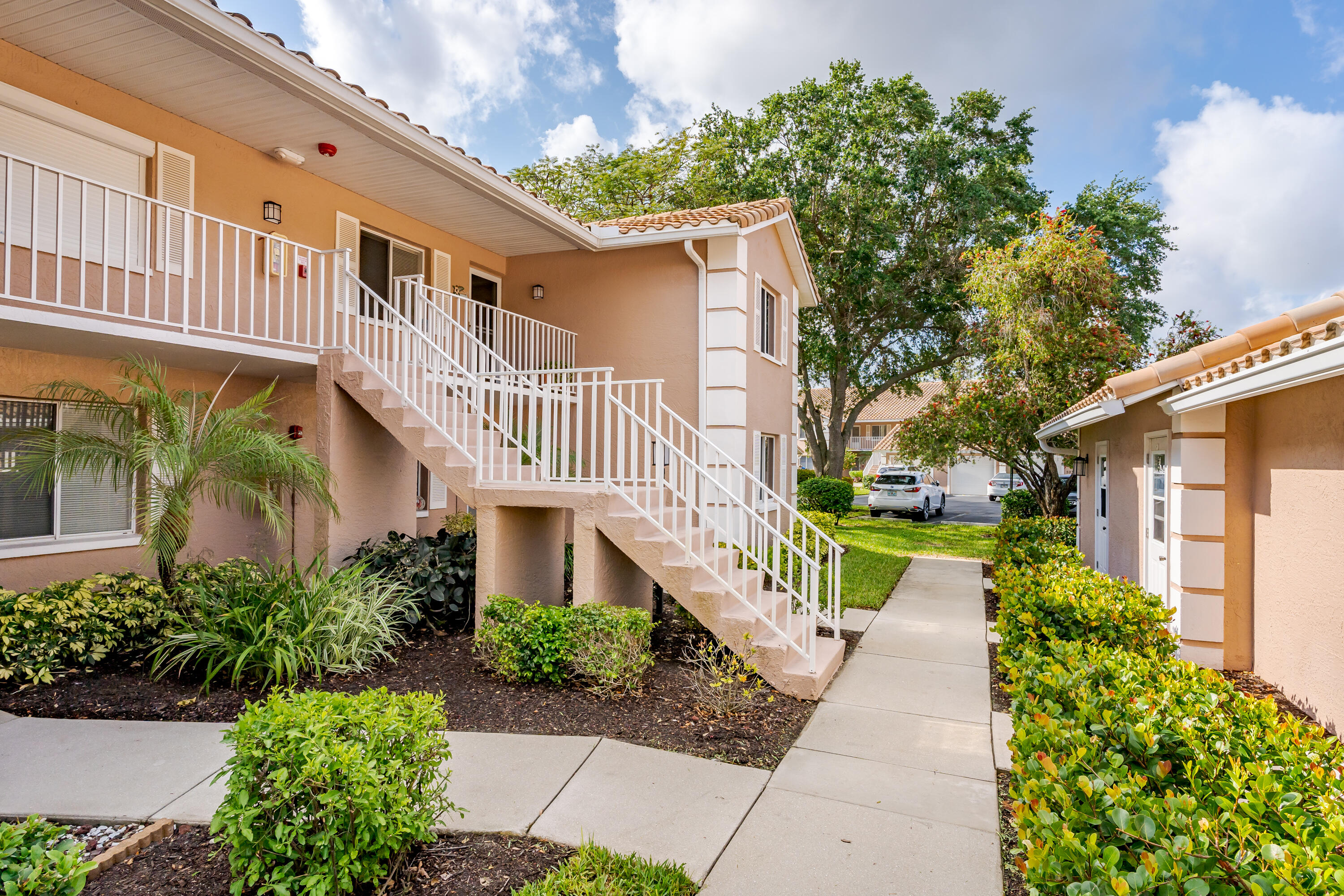 5936 Cranbrook Way, Unit B206 Naples, FL 34112 - Photo 1 of 2 a view of a house with brick walls plants and large tree