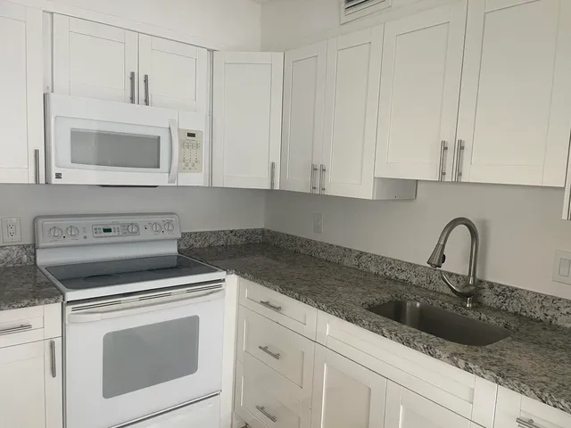 a kitchen with white cabinets and sink