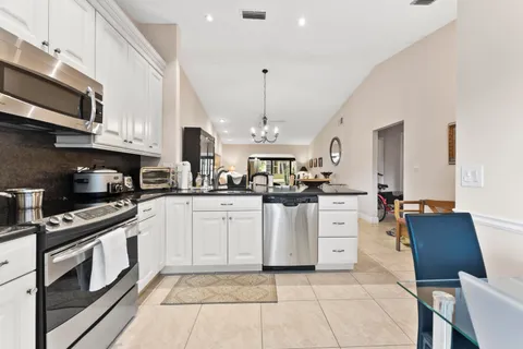 a kitchen with stainless steel appliances granite countertop a sink a stove top oven a chimney and a center island