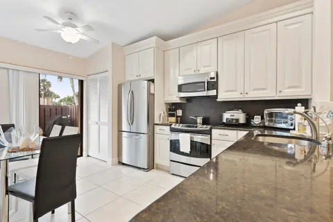 a kitchen with granite countertop a refrigerator a stove a sink and white cabinets