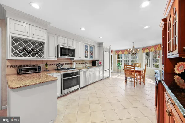 a kitchen with stainless steel appliances granite countertop a stove top oven a sink a dining table and chairs