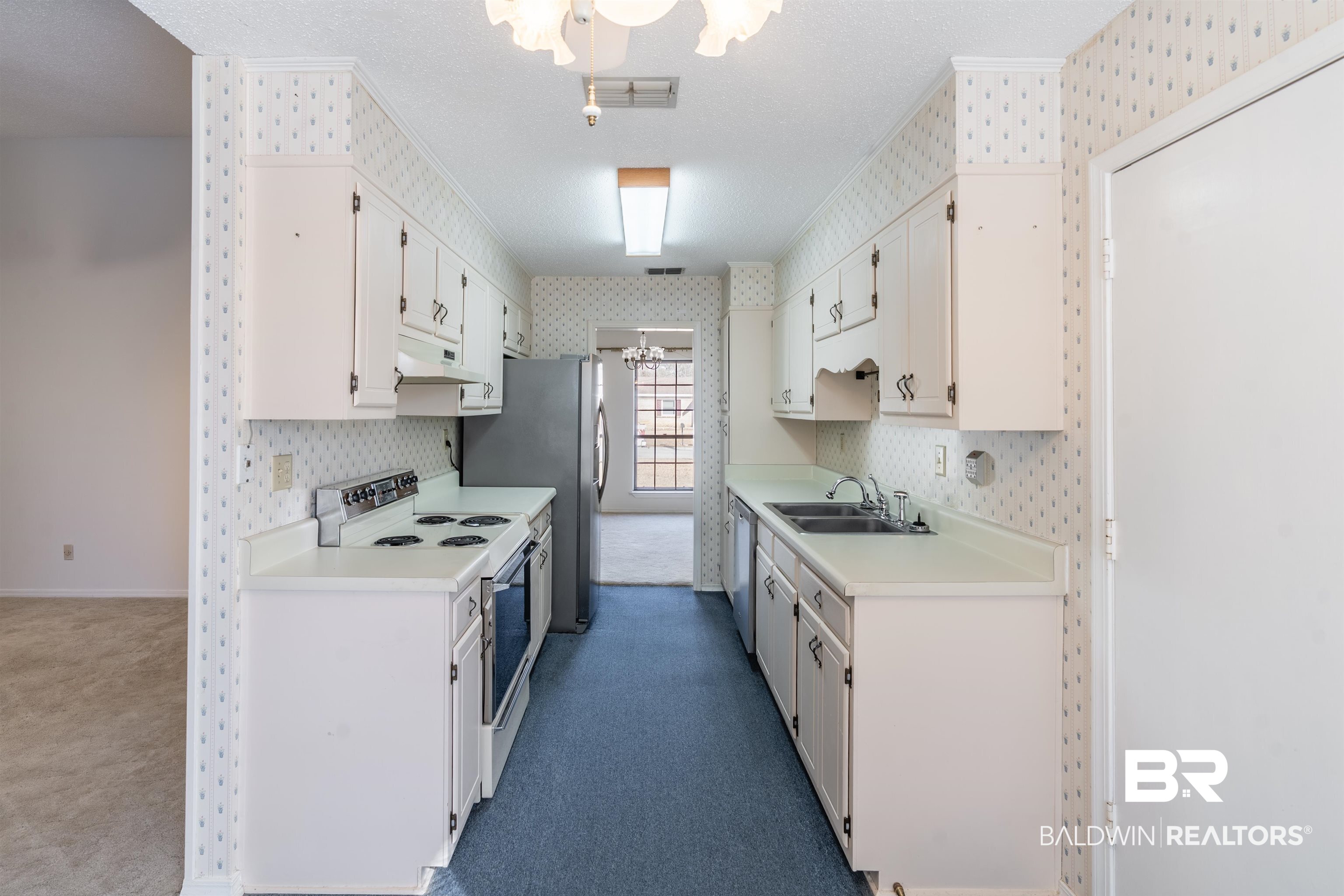 9751 Pine Knoll Road Mobile, AL 36608 - Photo 7 of 36 Kitchen featuring electric stove, light countertops, wallpapered walls, a textured ceiling, and white cabinets