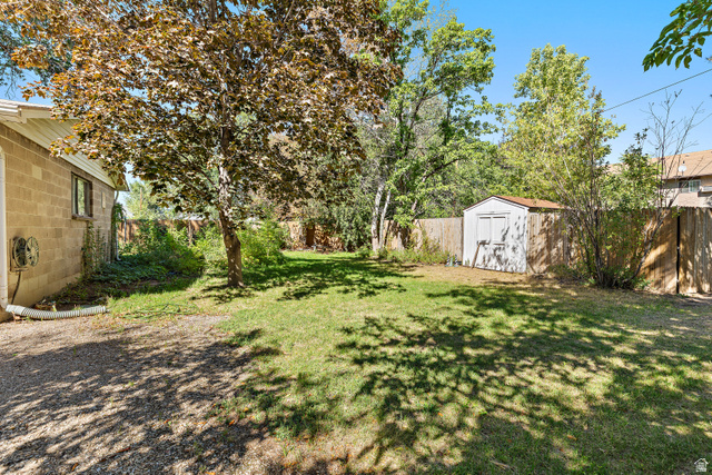 658 Wasatch Street Midvale, UT 84047 - Photo 26 of 31 Expansive backyard with a manicured lawn, established trees, and a functional storage shed