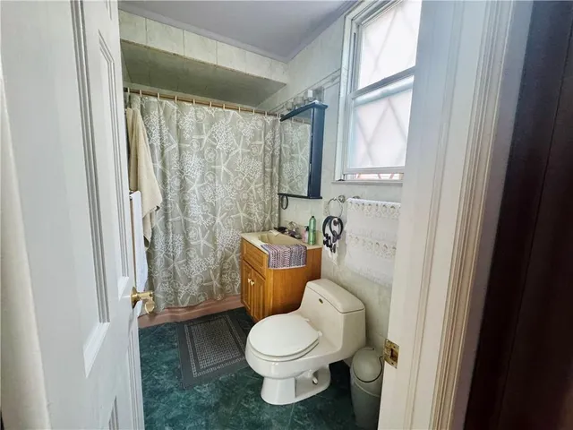 a white toilet sitting next to a bathroom sink and a window
