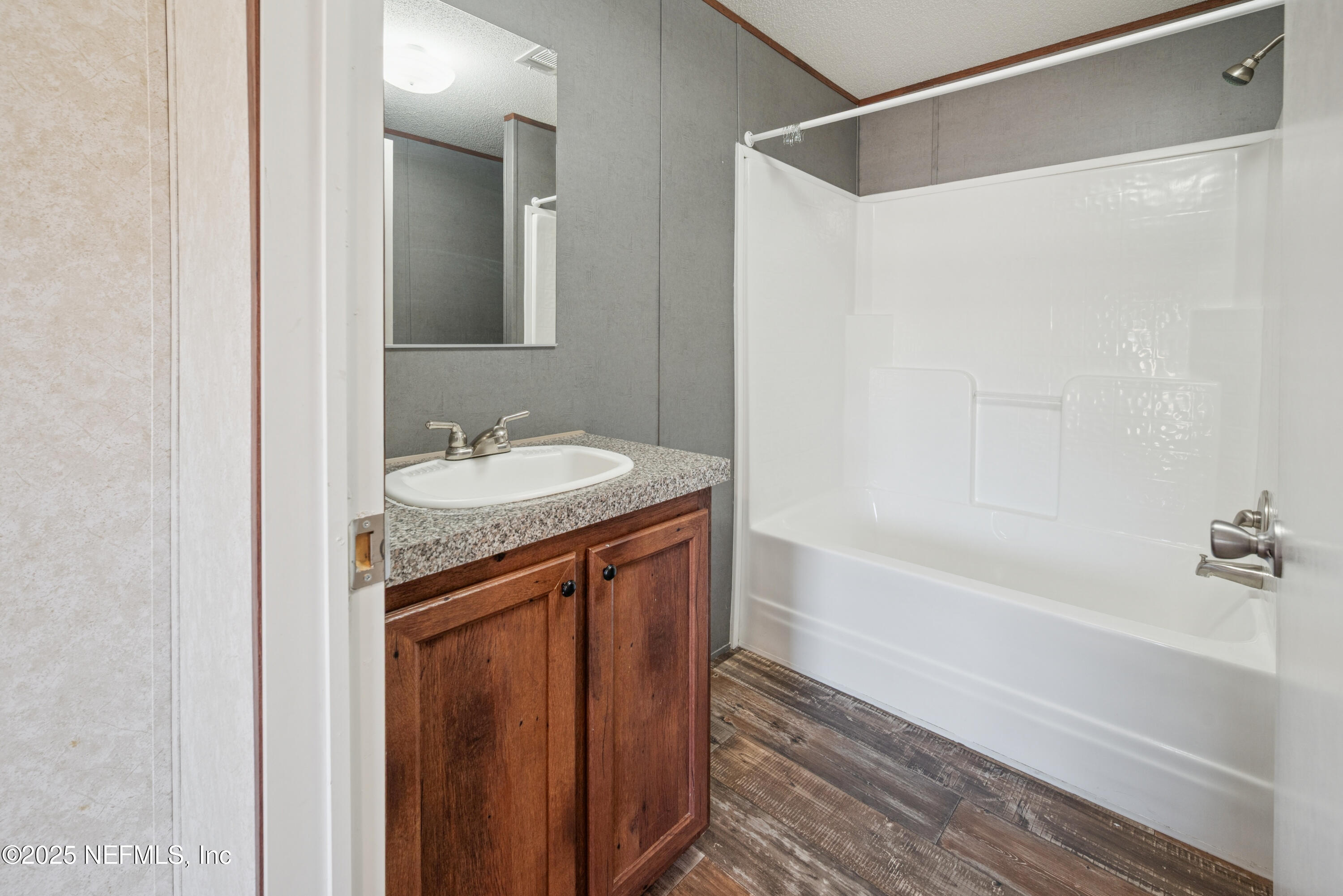 10379 Southwest 45th Place Lake Butler, FL 32054 - Photo 13 of 24 a bathroom with a granite countertop sink a mirror a shower and a bathtub